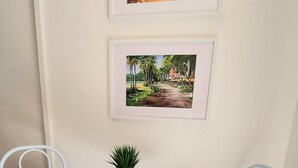 A small, white-framed room with two white chairs, a white table, and two framed pictures on the wall. - Luxury Spa Suite #220 Temple Palm Cove (Palm Cove)