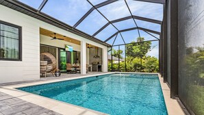 Une piscine avec un patio couvert, un ventilateur de plafond et du mobilier d’extérieur.