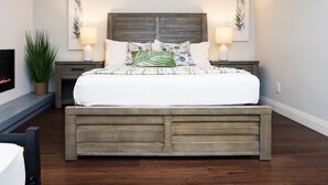 A bedroom with a wooden bed frame, white bedding, two bedside lamps, and a wall-mounted plant.