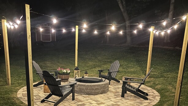 An outdoor patio area with a stone fire pit, two Adirondack chairs, and string lights. - 🏡Little Bear Cabin In Helen🐻 (Helen)