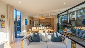 A modern living room with a sofa, dining table, and kitchen area.