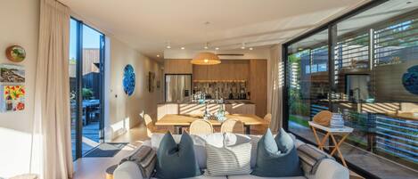 A modern living room with a sofa, dining table, and kitchen area.