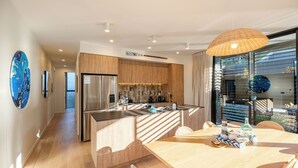 A modern kitchen with a central island, stainless steel appliances, and a dining area with a wooden table and chairs.