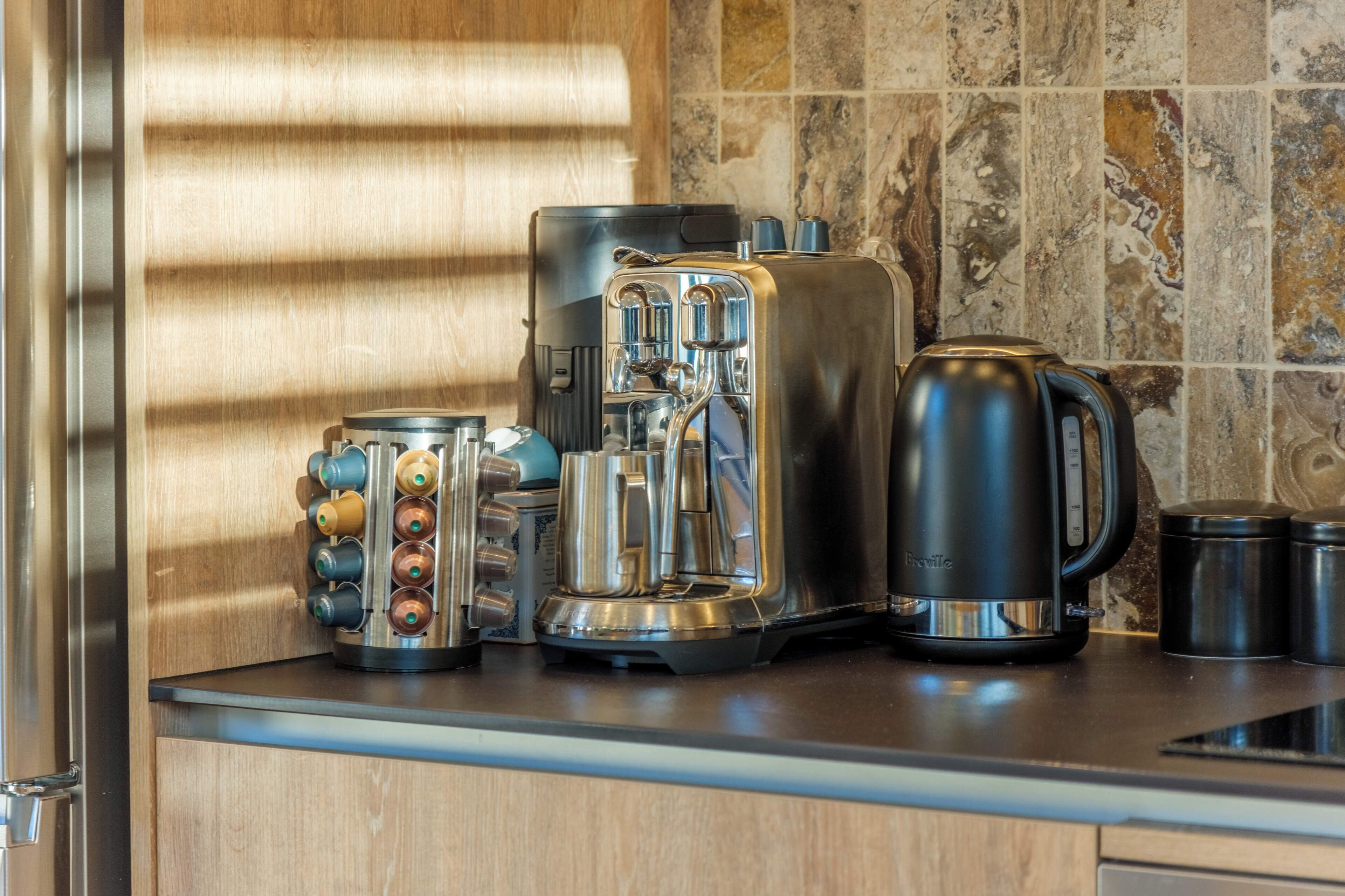 A kitchen counter with a coffee maker, a toaster, a kettle, and a coffee pot.