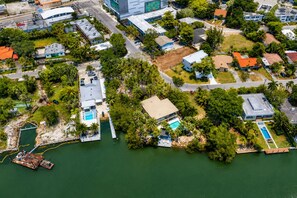 Vista aérea de una zona residencial costera con casas, un muelle y una piscina.