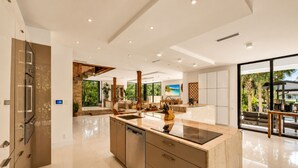 A modern kitchen with a central island, built-in appliances, and large windows offering a view of the outdoors.
