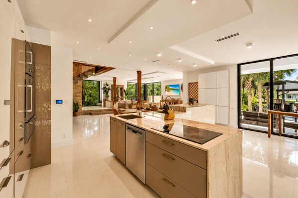 Una cocina moderna con una isla central, electrodomésticos integrados y ventanas amplias que ofrecen vistas al exterior.