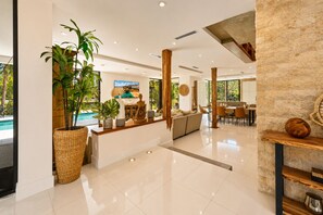 Un amplio vestíbulo de hotel con vista a la piscina, una recepción y un comedor.