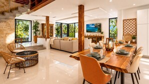A modern dining area with a wooden table, cushioned chairs, and a view of the outdoors.