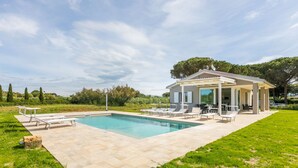 Ein moderner Poolbereich im Freien mit Liegestühlen und einer überdachten Terrasse.