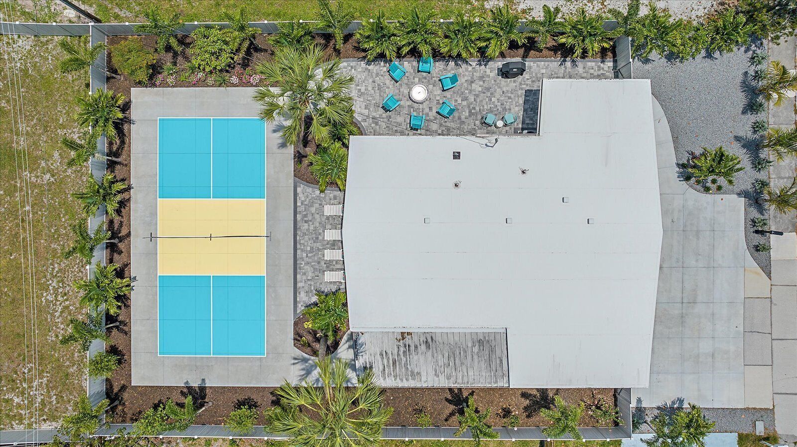 An aerial view of a building with a rooftop pool, surrounded by greenery and a patio area with seating.