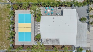 An aerial view of a building with a rooftop pool, surrounded by greenery and a patio area with seating. - The Palmy Pickle w/ Pickleball Court + Fire Pit! (Sarasota)