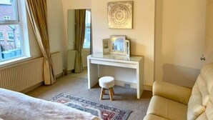 Ein Schlafzimmer mit Bett, Schreibtisch, Stuhl, einer Deckenleuchte und Blick ins Freie.