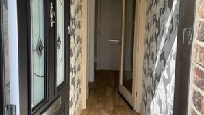 Ein Korridor mit Holzboden, einer schwarzen Tür mit Glasfeldern und Wandtapete mit Muster.