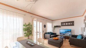 A modern living room with a glass dining table, leather sofas, a flat-screen TV, and a large window with sheer curtains. - Casa Turquesa by Solset (Torrox)