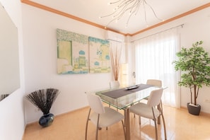 A dining area with a glass table, four chairs, and two paintings on the wall. - Casa Turquesa by Solset (Torrox)