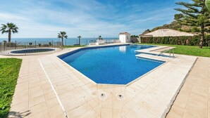 A rectangular swimming pool with a tiled deck, surrounded by palm trees and a view of the sea. - Casa Turquesa by Solset (Torrox)