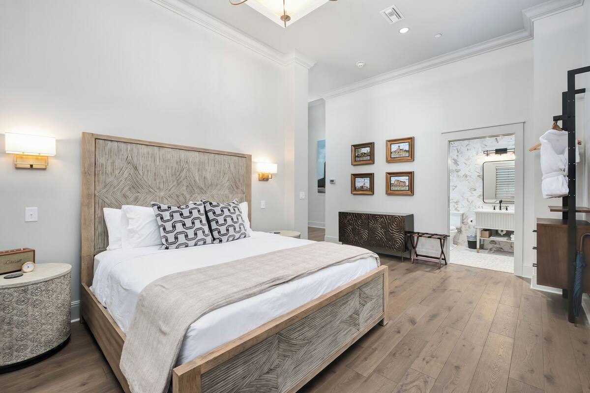 A modern bedroom with a large bed, bedside lamps, and a view into the bathroom.