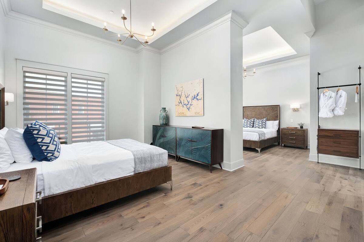 A modern bedroom with a large bed, a dresser, and a vanity.