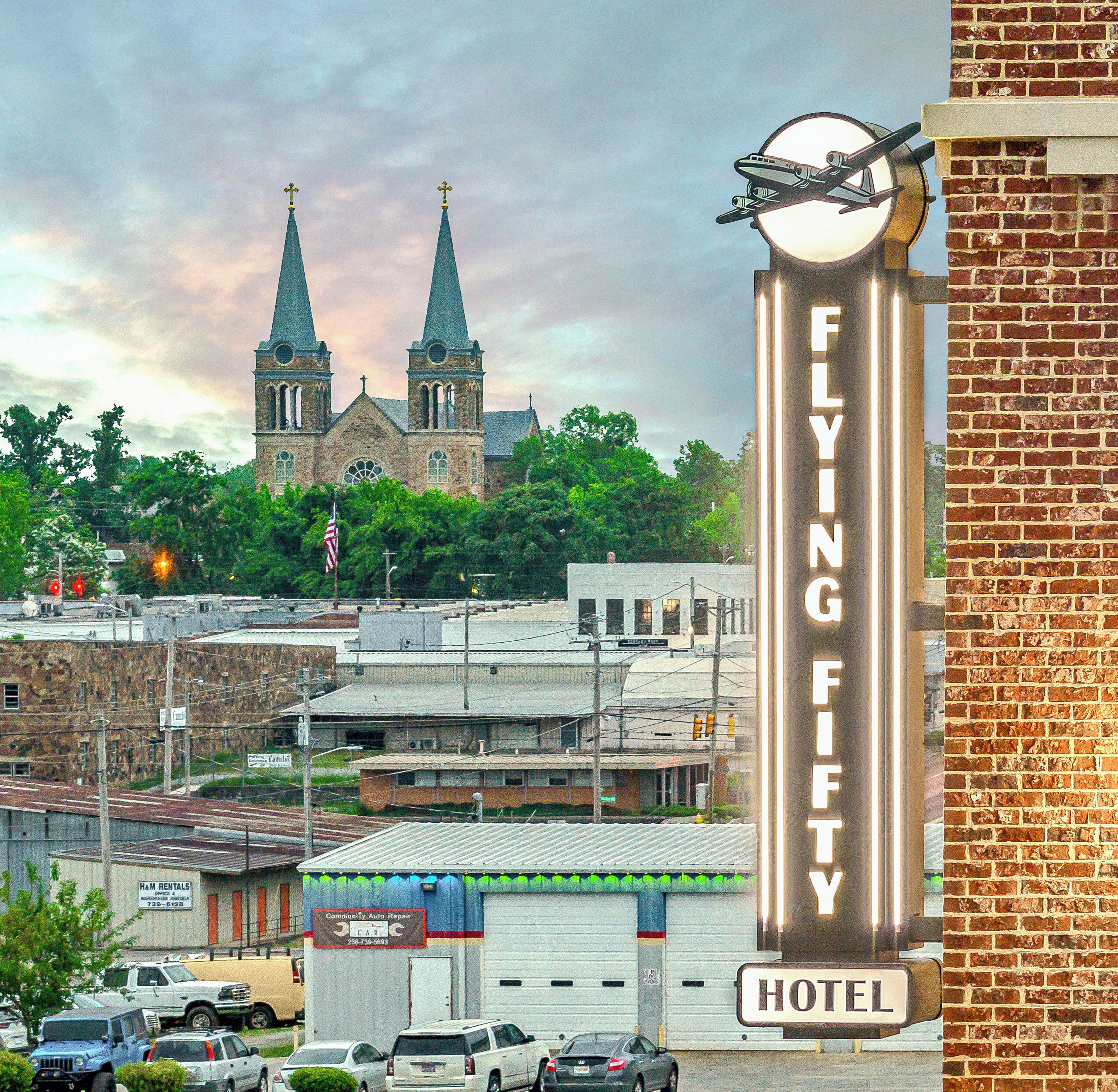 A hotel sign with a clock and a flying fifty sign.