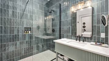 A modern bathroom with a glass shower enclosure, a vanity with a mirror, and a towel rack.