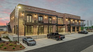 A modern hotel with a brick facade, large windows, and a covered outdoor area. - The Flying Fifty, a Luxury Boutique Hotel (Cullman)