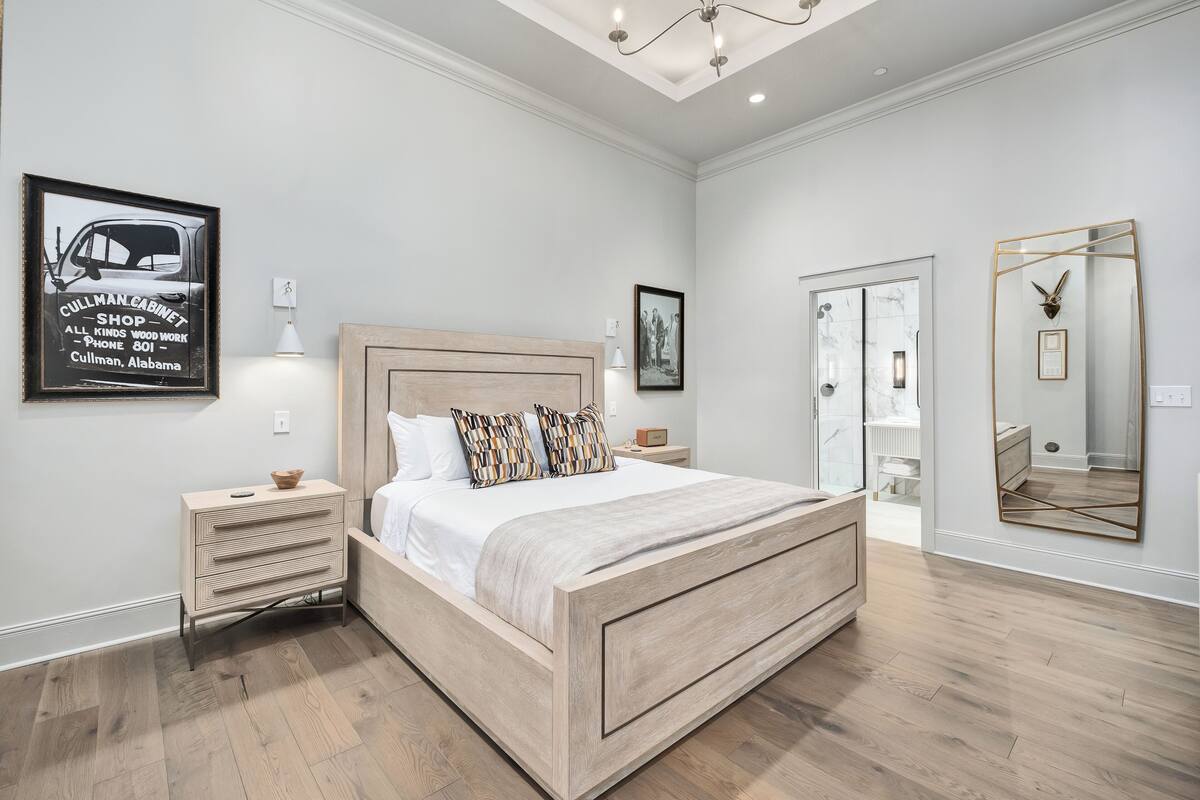 A bedroom with a wooden bed, bedside tables, a large mirror, and a framed picture on the wall.