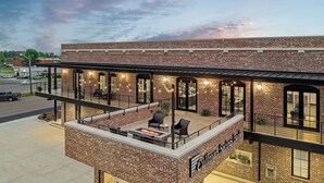 A brick building with a covered outdoor seating area and a fire pit. - The Flying Fifty, a Luxury Boutique Hotel (Cullman)