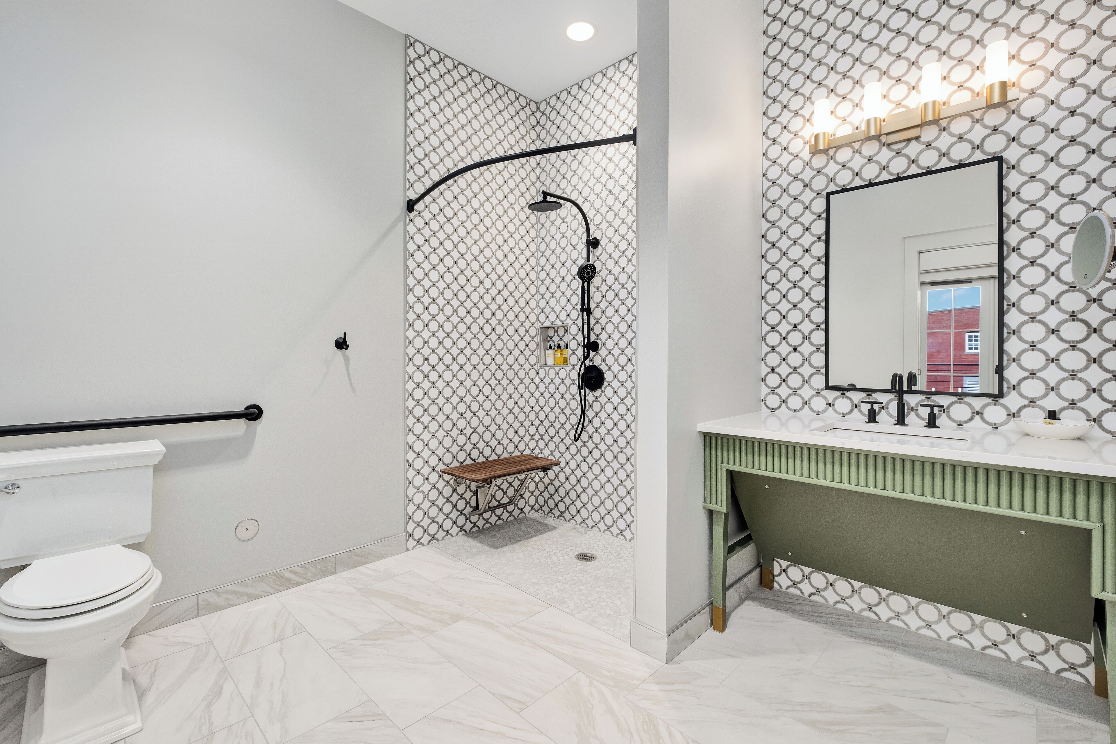 A bathroom with a toilet, shower, and vanity with a mirror.
