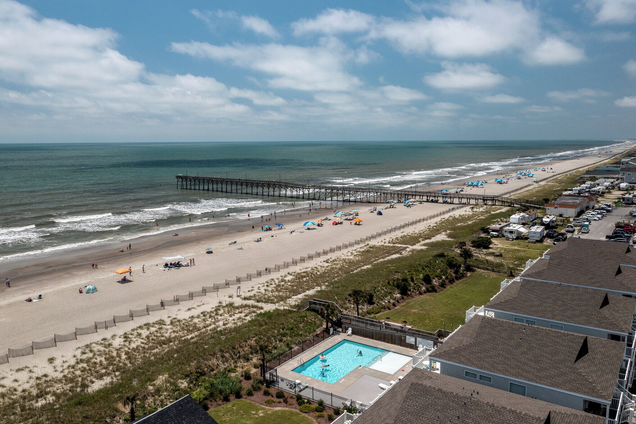 Ein Strand mit einer Mole, einem Schwimmbad und Strandsonnenschirmen.