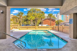 Una piscina con vistas a palmeras y edificios al fondo.