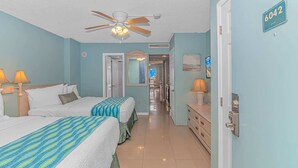 Une chambre d’hôtel avec deux lits, un ventilateur de plafond, un couloir avec une porte et un numéro de chambre affiché sur le mur.