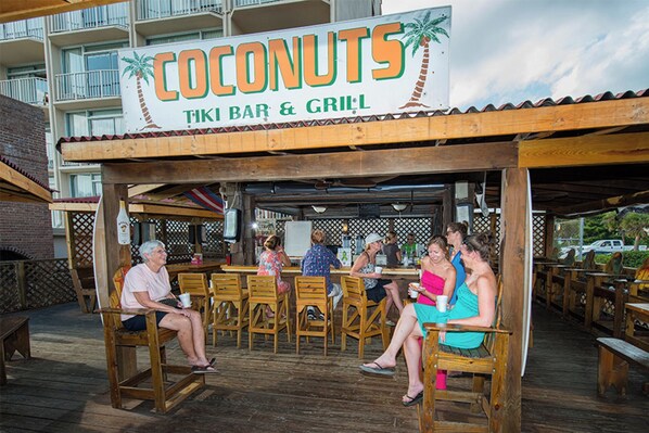 A tiki bar named "Coconuts" with outdoor seating and a wooden deck.