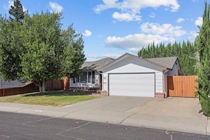 Simple, single-story home with a garage and front porch, set amidst a well-manicured lawn.