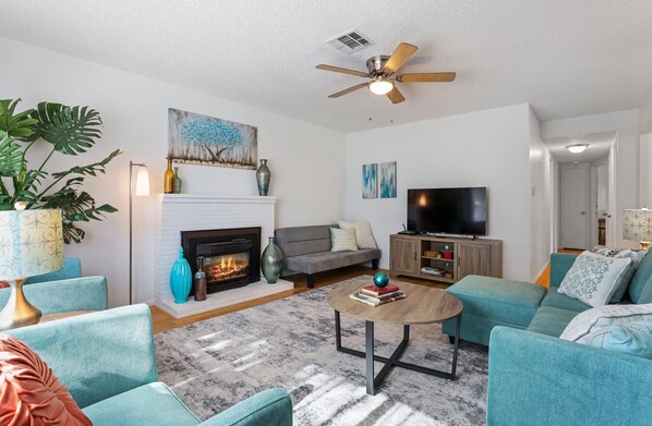 A living room with a fireplace, sofa, TV, and ceiling fan. - Trinity Escape, Entire home, 3 bedroom, 2 bath near Lodi Lake (Lodi)