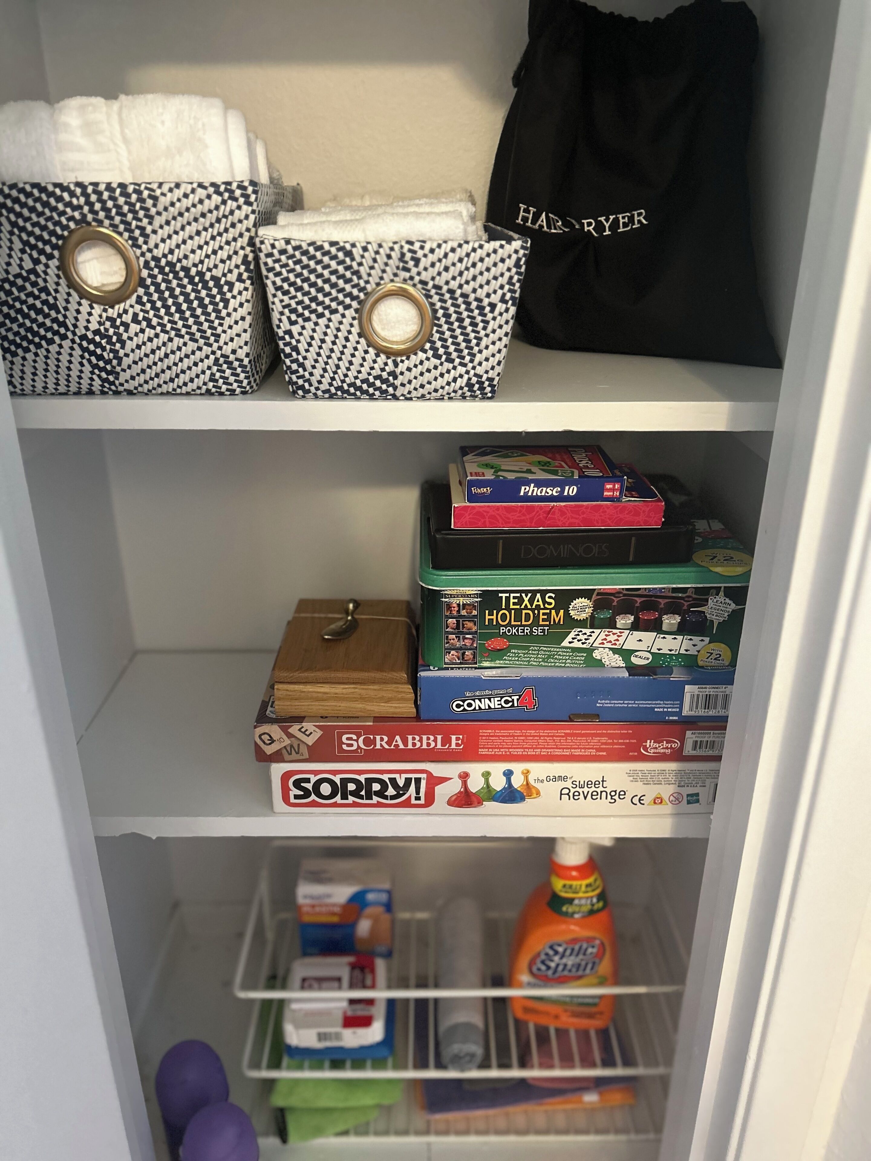A storage shelf with various board games and a bottle of Sprite.