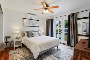 Relax in comfort with a large bed, bedside tables, and a ceiling fan above, surrounded by a beautiful view.