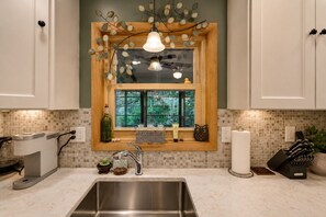 A kitchen with a built-in window, a stainless steel sink, and a coffee machine.