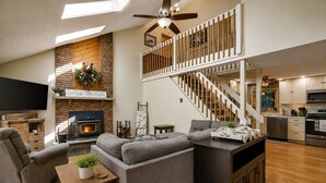A spacious living area with a fireplace, a sofa set, a television, and a kitchen with modern appliances. - New Listing: On the Rocks in the Hideout (Lake Ariel)