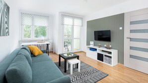 A modern living room with a sofa, a small table, a TV, and a cabinet. - Olsza Comfy Apartment (Kraków)