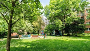 A park with a playground, benches, and trees. - Olsza Comfy Apartment (Kraków)