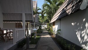 A narrow pathway flanked by buildings with tiled roofs and lush greenery.