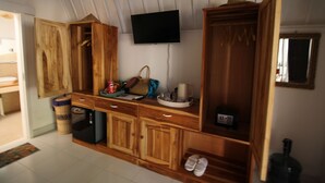 A room with wooden cabinets, a television mounted on the wall, and a small table with various items.