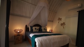 A bedroom with a canopy bed, a bedside lamp, and palm tree wall art.