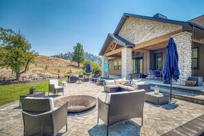A patio area with outdoor furniture, a fire pit, and a stone building with a covered seating area.