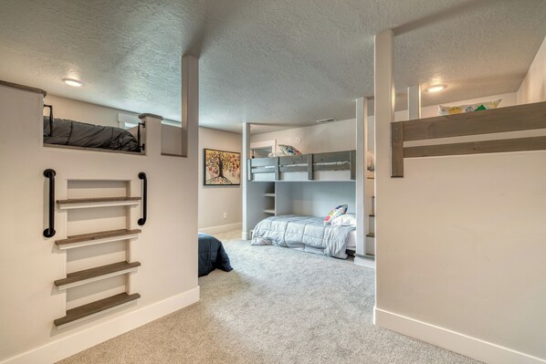 A compact, multi-level room with bunk beds, built-in shelves, and a carpeted floor.
