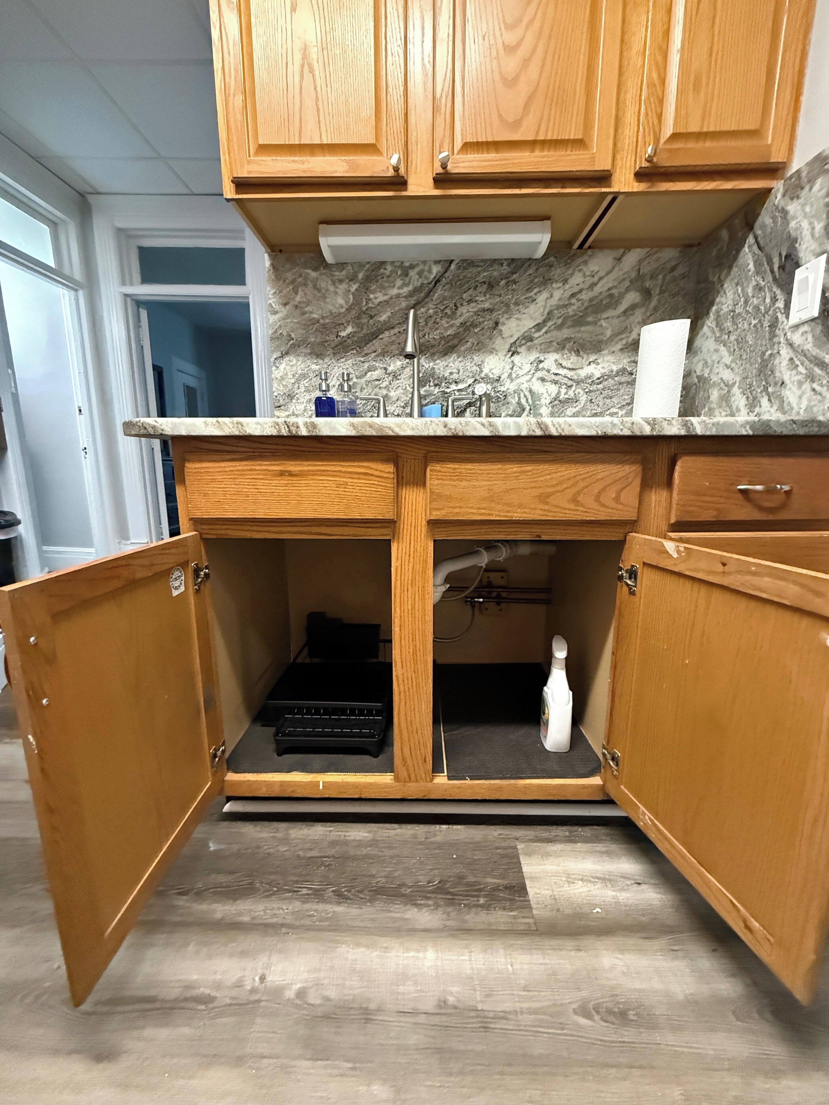 A kitchen with wooden cabinets, a marble countertop, and a built-in sink.