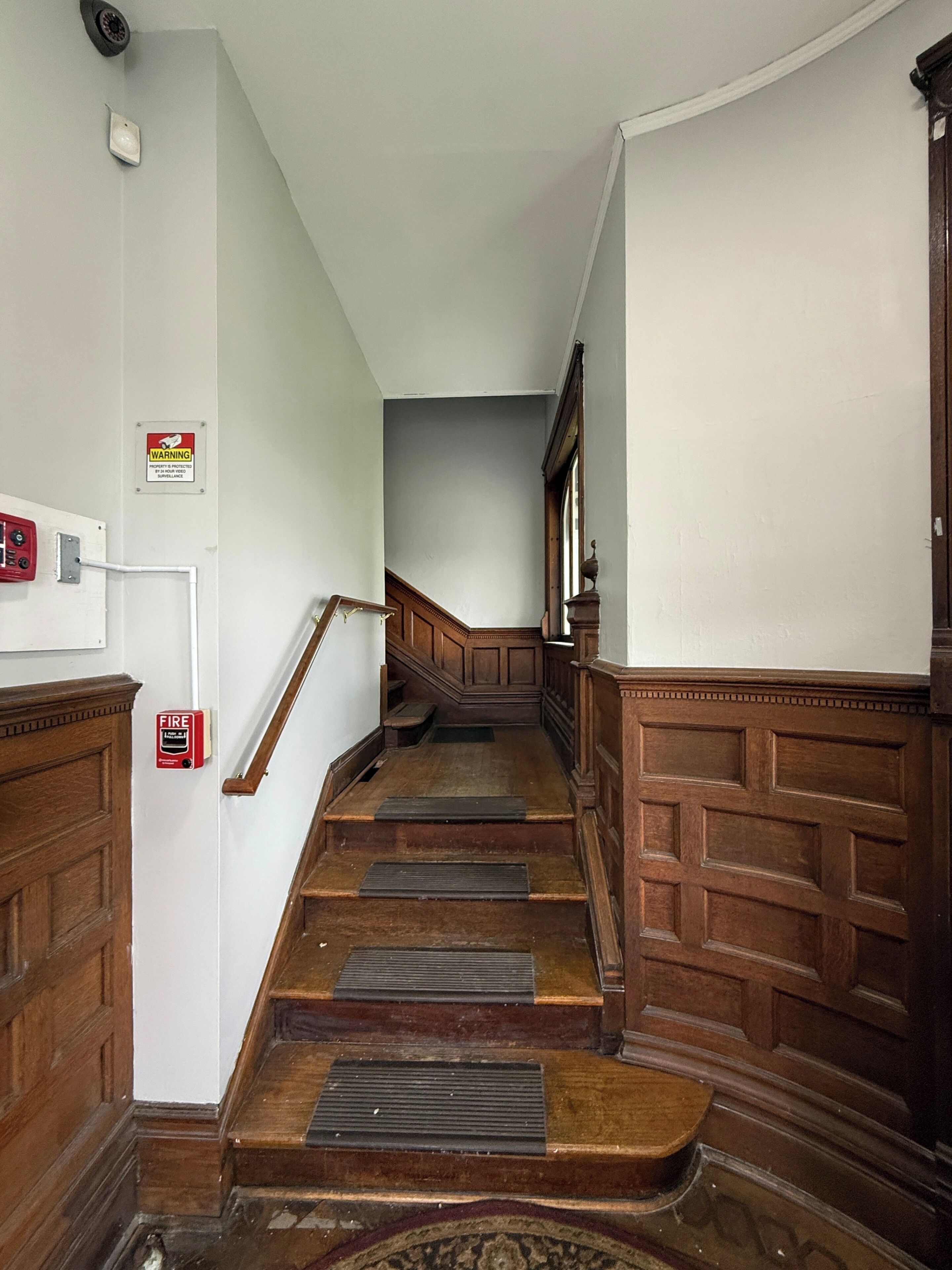 Una escalera de madera con barandilla, que conduce a un rellano con una puerta.