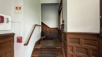 Una escalera de madera con barandilla, que conduce a un rellano con una puerta.