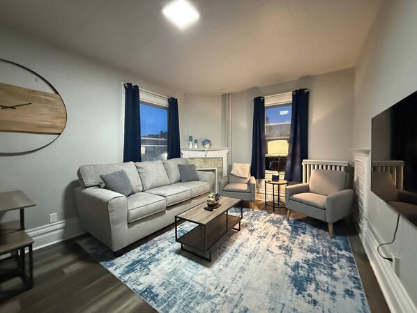 A modern living room with a sofa, armchairs, a coffee table, and a fireplace.